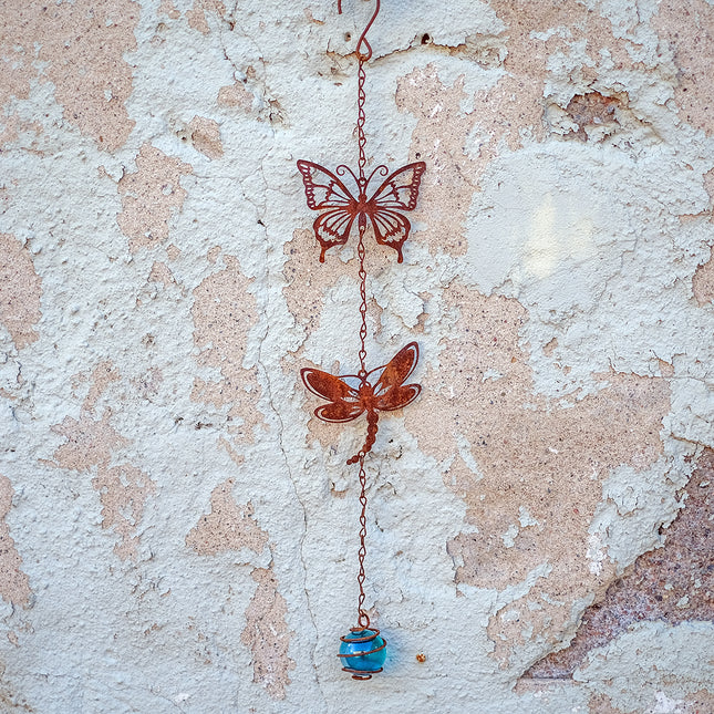 Rostigt hänge med fjäril, trollslända och glaskula